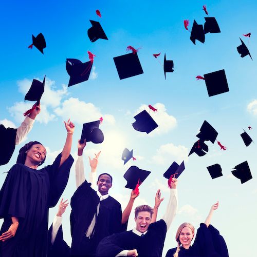 Graduating high school students throw their hats up in the air in celebration.