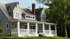 A large grey house with a white wraparound porch