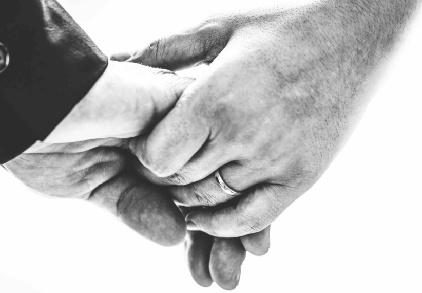 A close up on the interlinked hands of a married couple who is holding hands